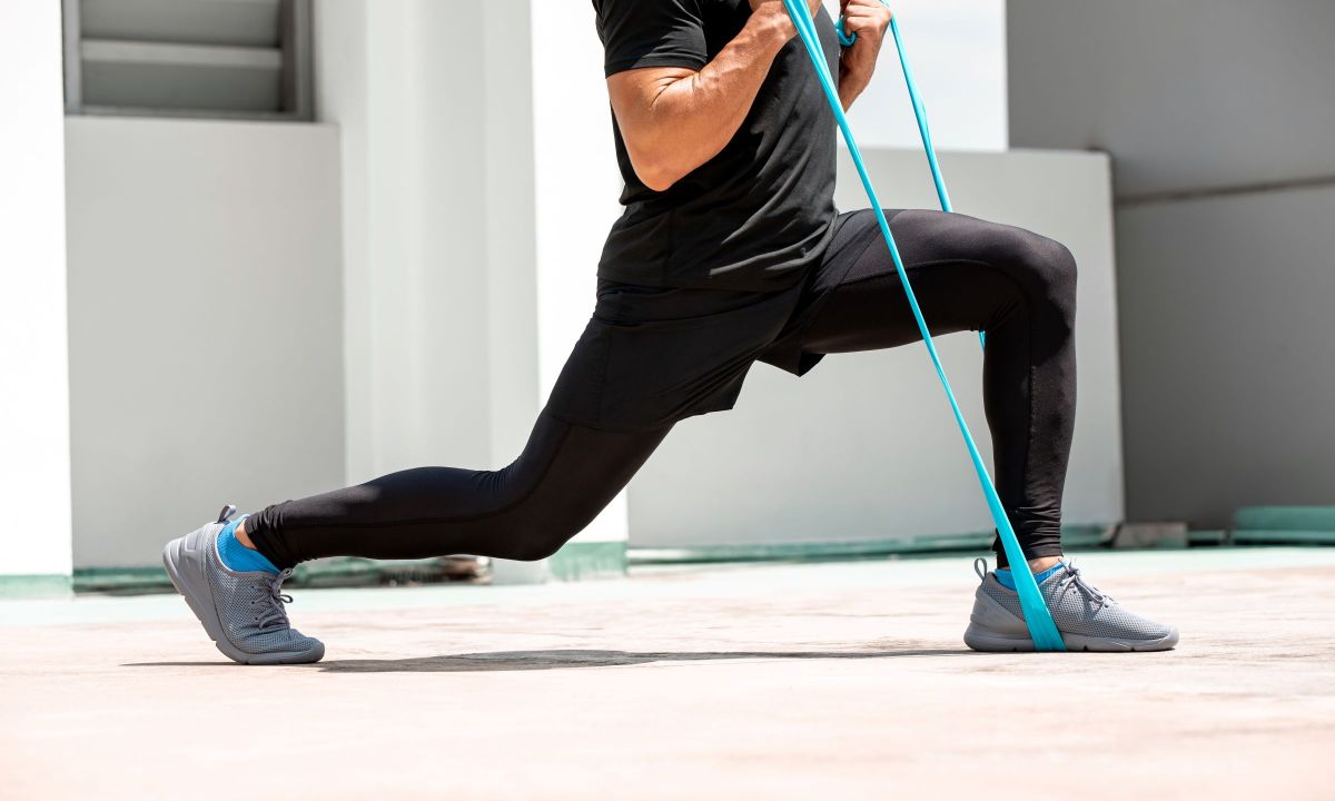 man doing lunge exercise with resistance band indoors