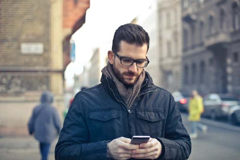 man looking at phone in city during winter