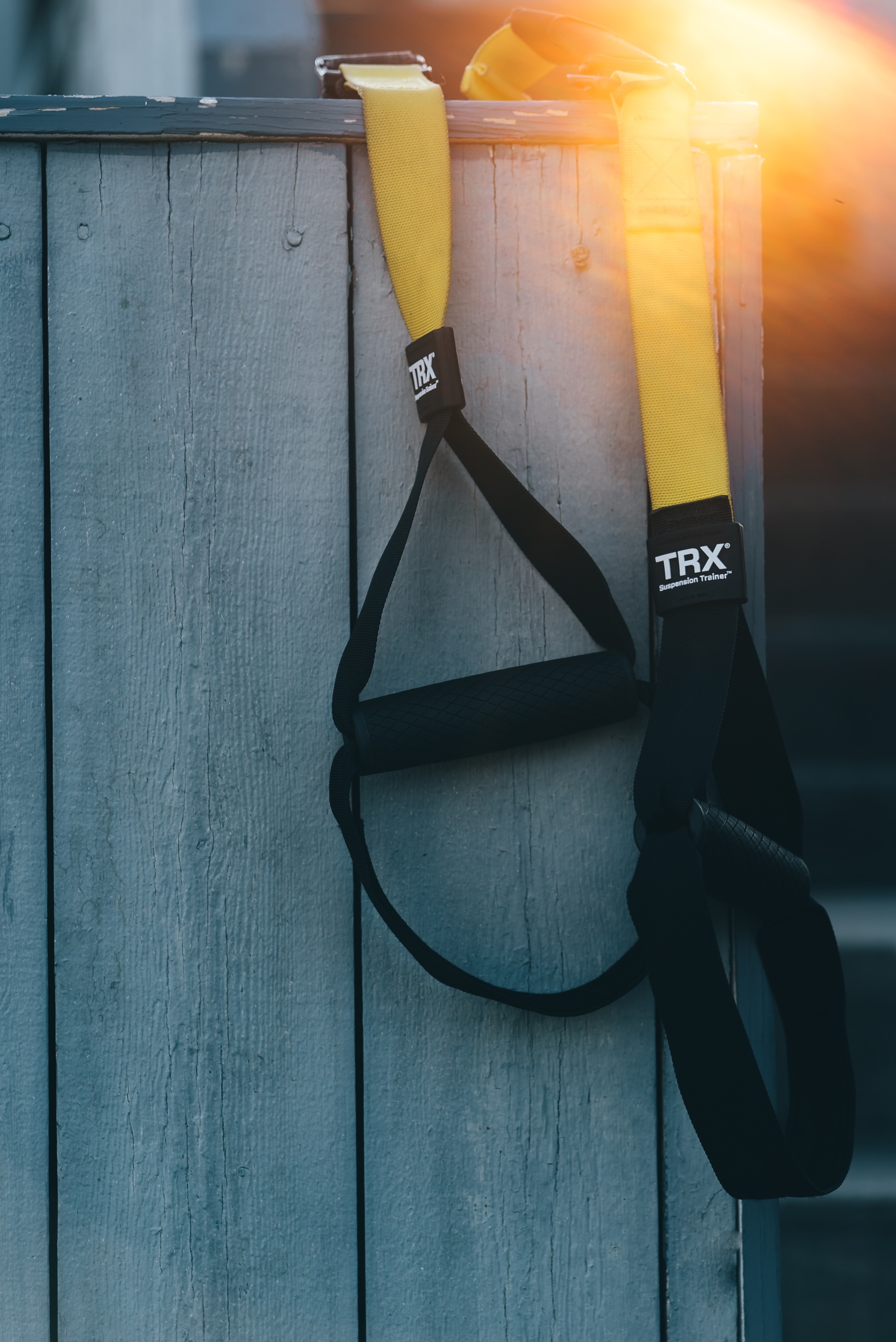 yellow resistance bands with black handles hanging over wooden fence