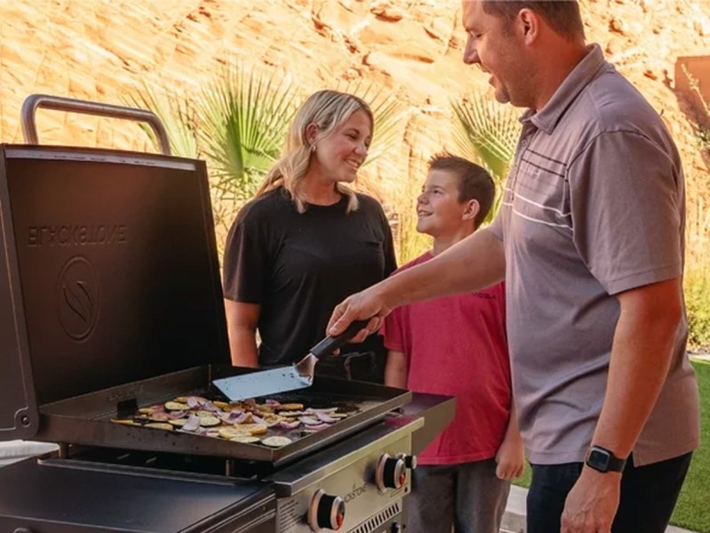 A family cooks on the Blackstone 28-inch propane griddle with air fryer.