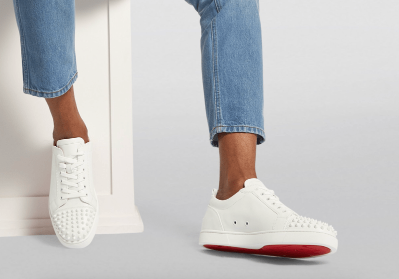 Someone wearing a pair of Louboutin's Junior Spikes Calfskin Sneakers.