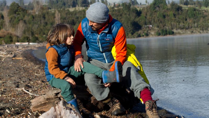 A man and child wearing Patagonia vests by a lake.