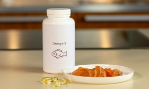 fish oil bottle and supplements and fish on a white plate on white table in kitchen