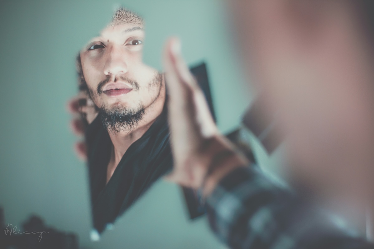 man looking into a mirror with teal paint