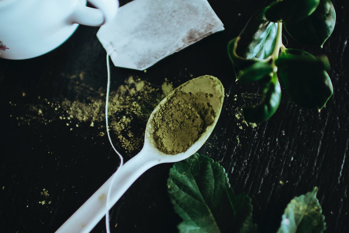 green tea leaves in spoon and in a bag on table
