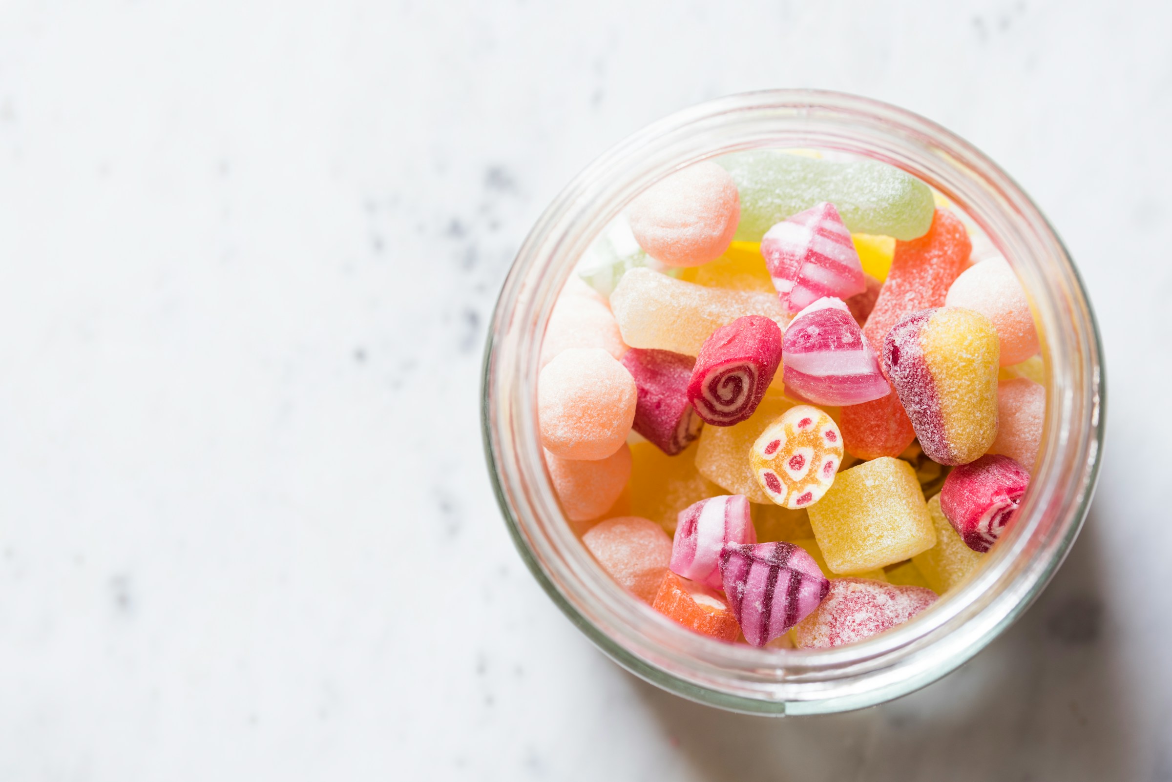 candy sugary colorful treats in glass jar on white table