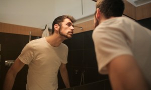 A man looking in the bathroom mirror