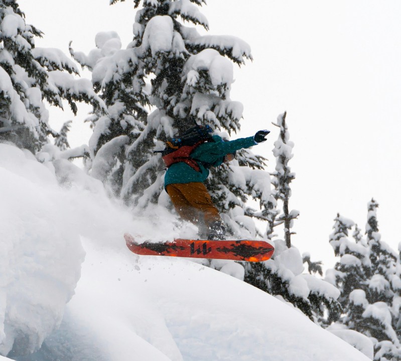 Snowboarder jumping through powder glades