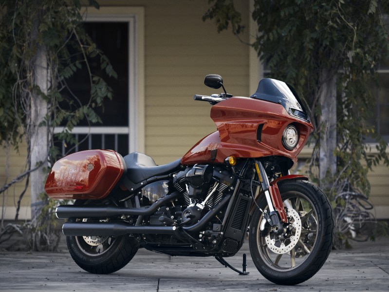 2024 Harley-Davidson Low Rider ST in Red Rock parked right front three-quarter shot with a yellow house in the background.