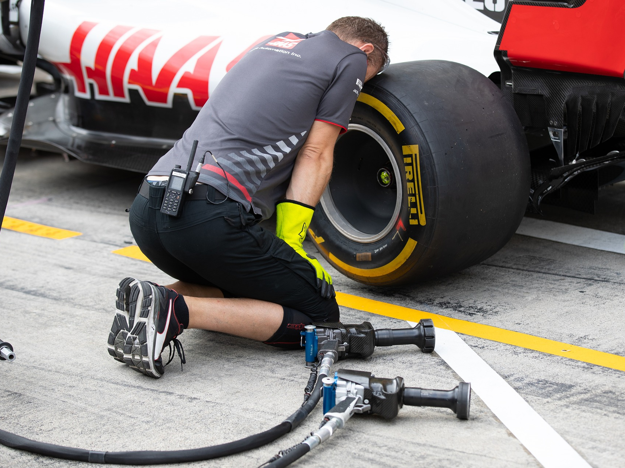 Desmontadora de neumáticos Hass Racing F1 con un coche de carreras de F1 apoyando la cabeza en un neumático de coche de carreras Pirelli F1.