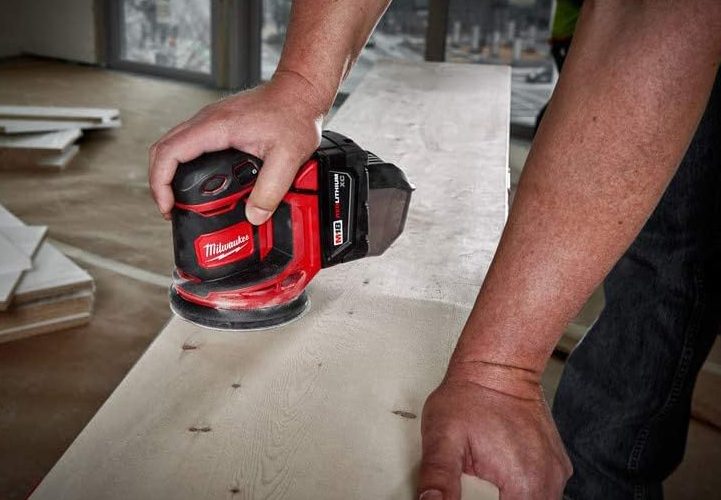 Someone using the Milwaukee Orbit Sander in a warehouse.