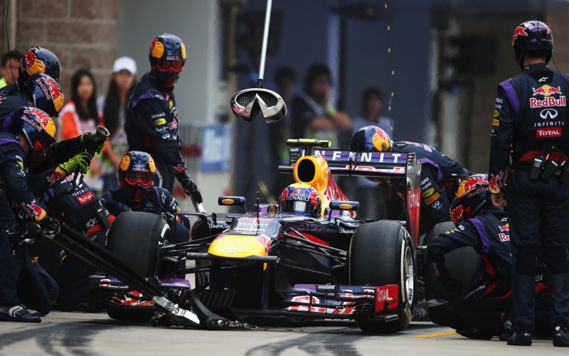 Red Bull F1 race car in pit for tire change with pit crew in motion