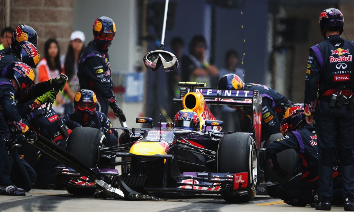 Red Bull F1 race car in pit for tire change with pit crew in motion