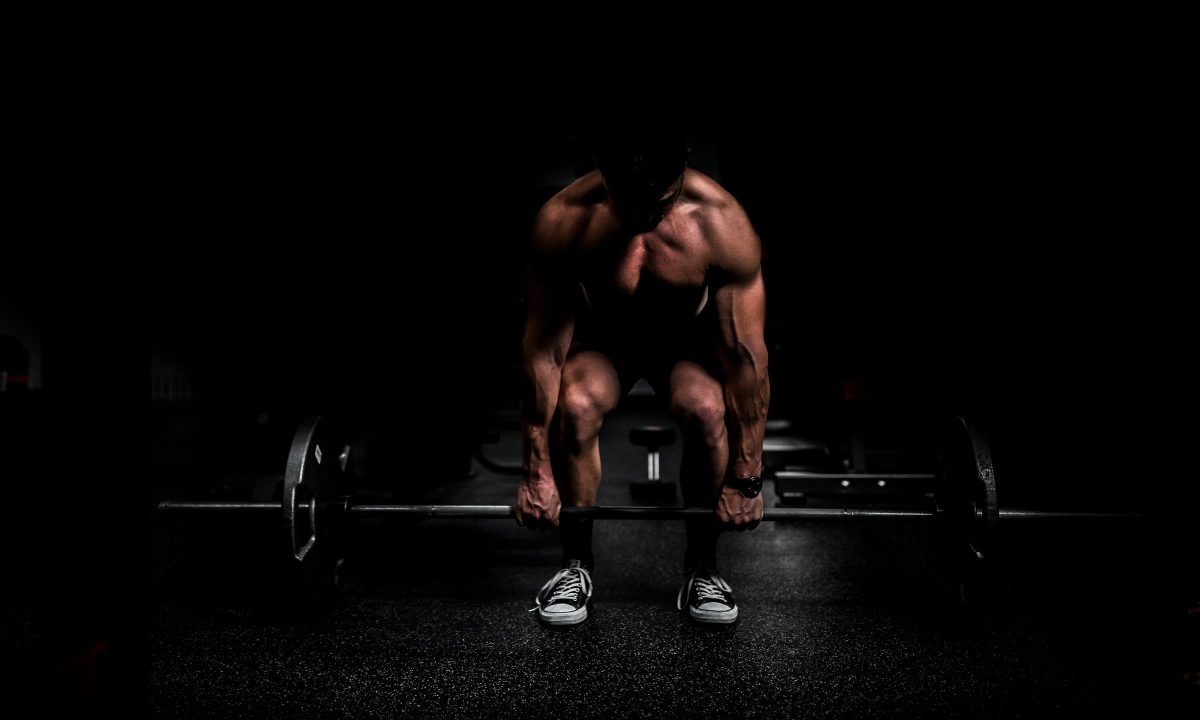 Shirtless man doing a deadlift weight lifting exercise with black background