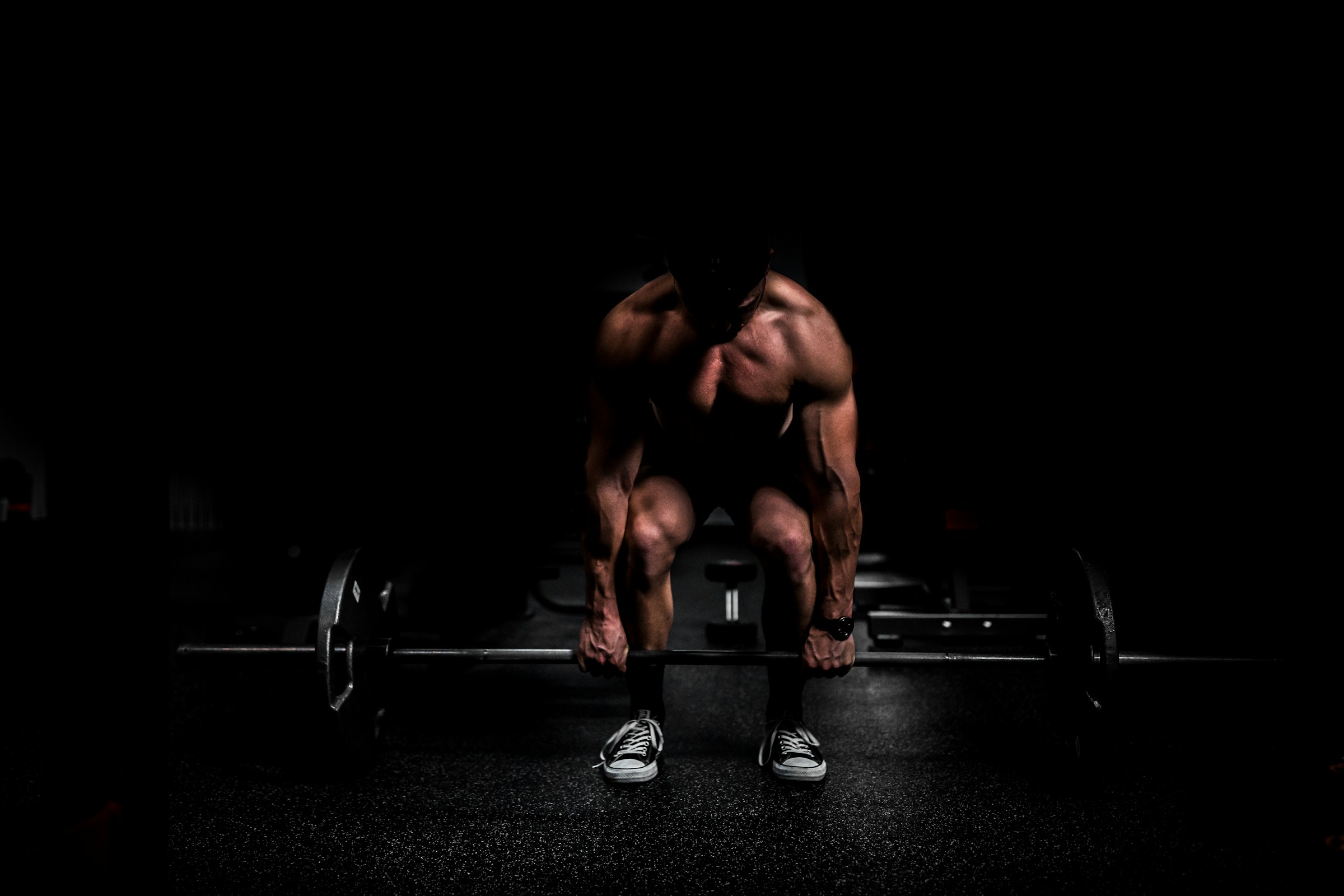 Shirtless man doing a deadlift weight lifting exercise with black background