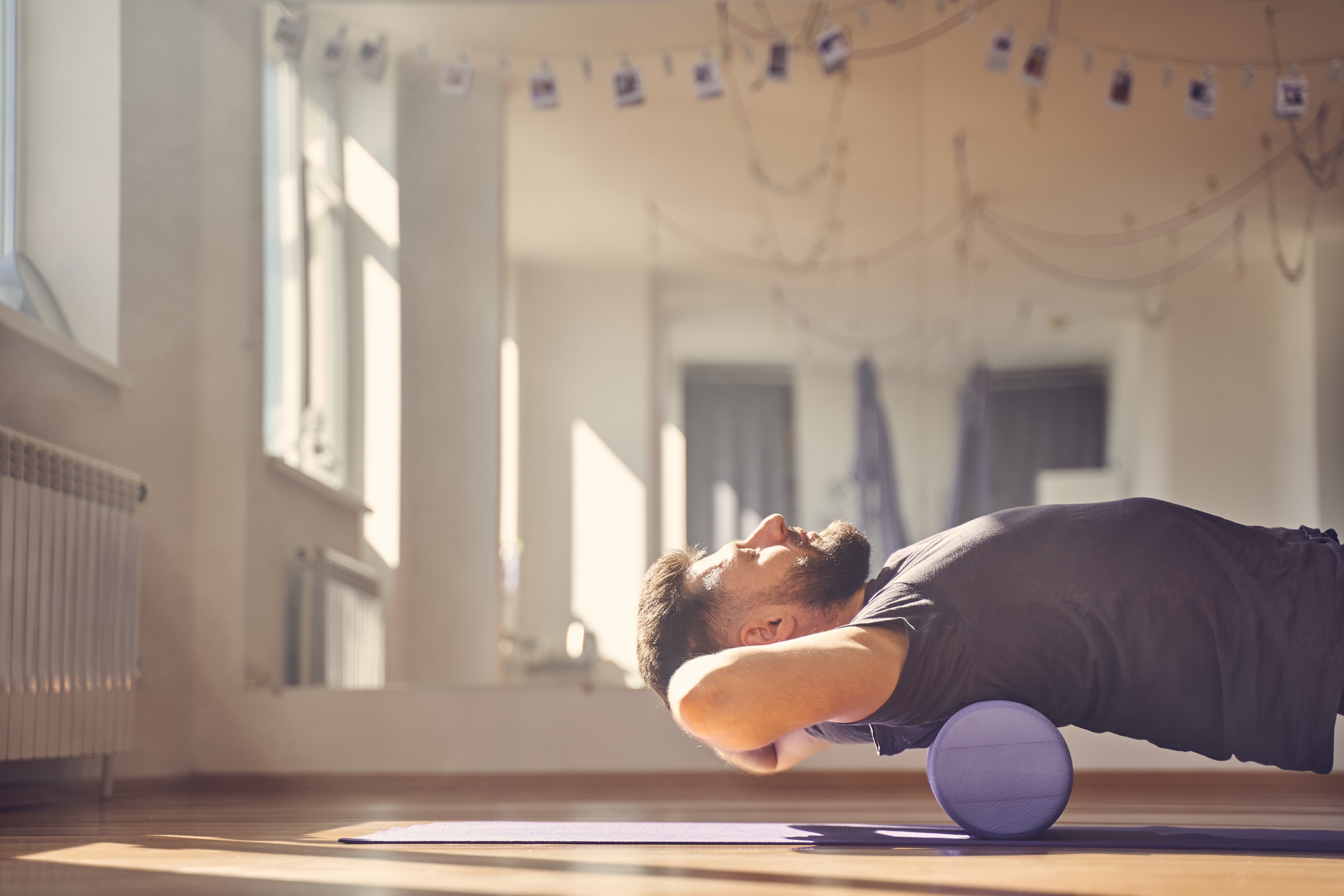 Handsome young man doing exercise with muscle therapy foam roller