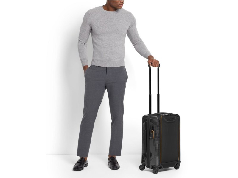 Man holding Tumi luggage by the handle.