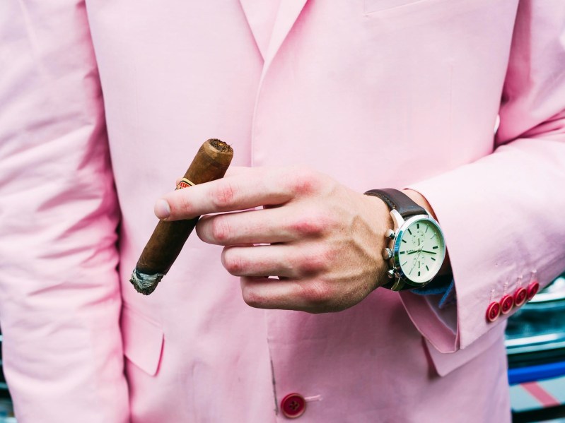 Man in pink suit smoking and enjoying what a cigar tastes like.