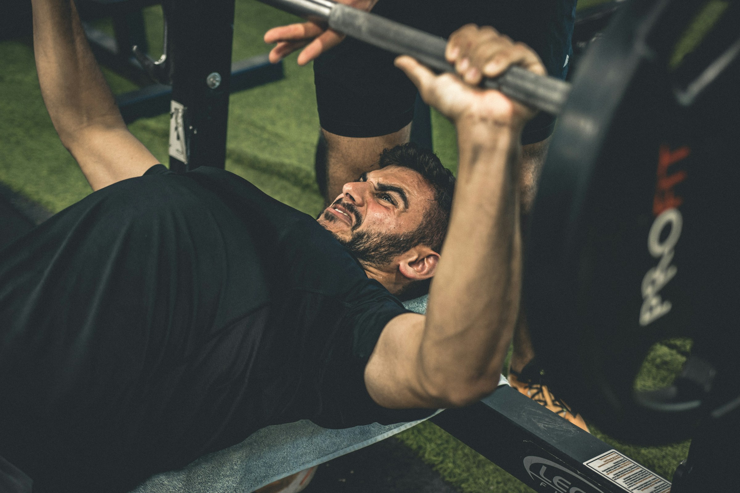 man wearing black shirt laying on bench in gym lifting weights