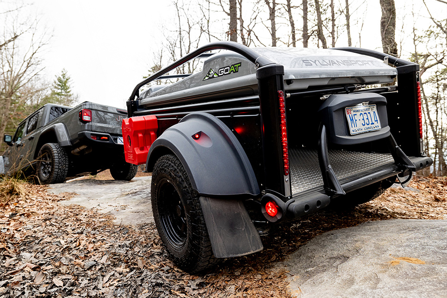 Rear view of SylvanSport's GO All-Terrain Camper Trailer being towed by a Jeep.