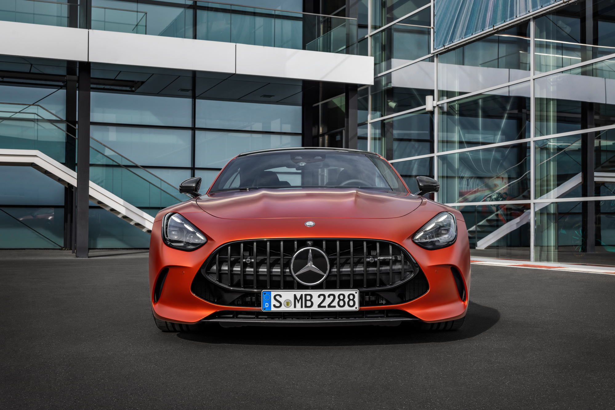 2025 Mercedes-AMG GT 63 S E Performance direct front view parked in front of a glass-walled building.