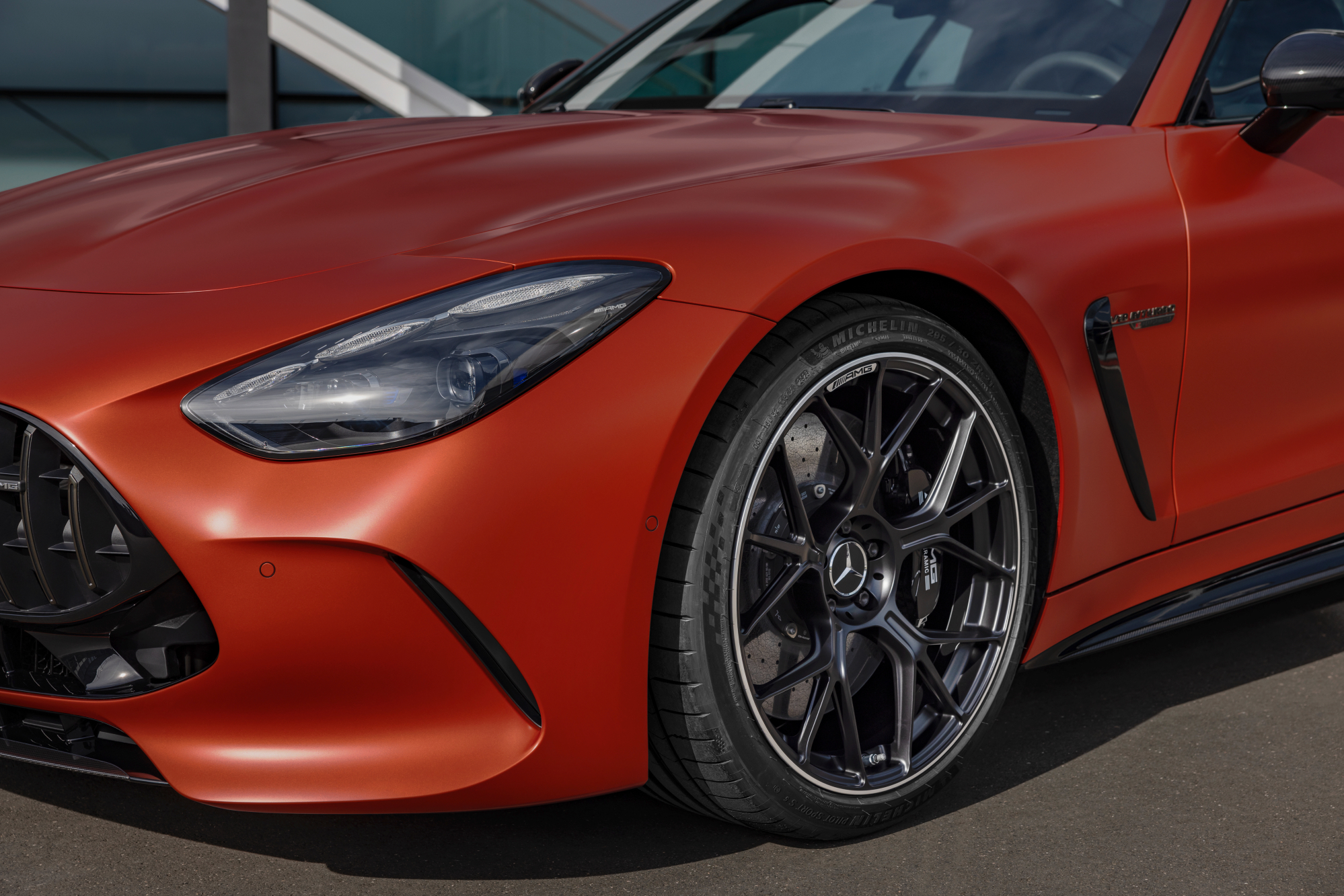 2025 Mercedes-AMG GT 63 S E Performance left front quarter view of bumper, fender,and wheel parked in front of a glass-walled bu