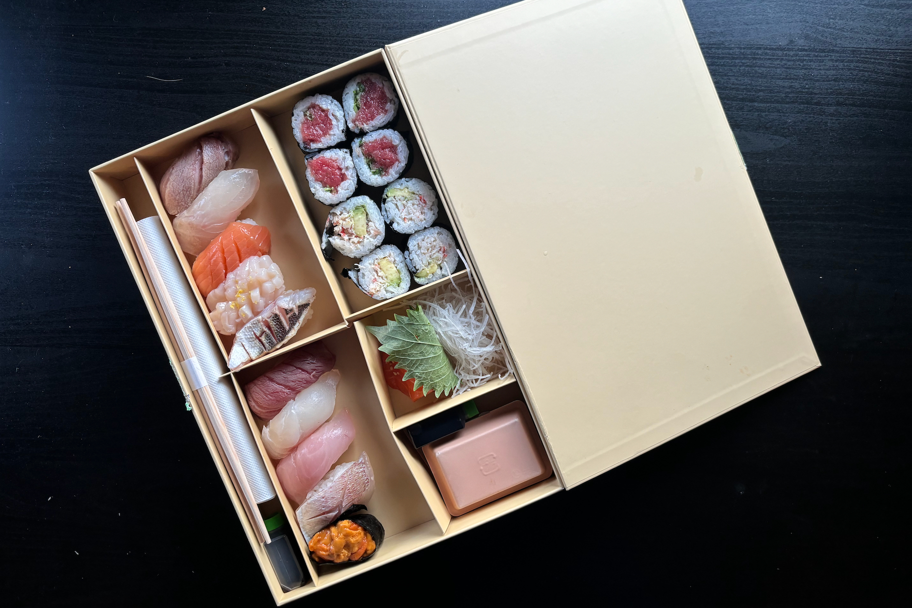 Joji box sushi on black table.