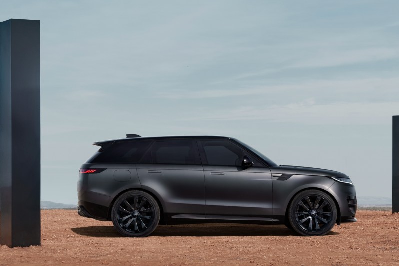 Right side profile shot of a 2025 Range Rover Sport Dynamic SE with Stealth Pack parked on desert sand between two black monoliths.