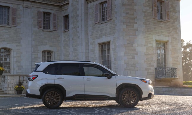 Right side profile shot of a 2025 Subaru Forester parked on a stone drive in front of a multiple story stone mansion.