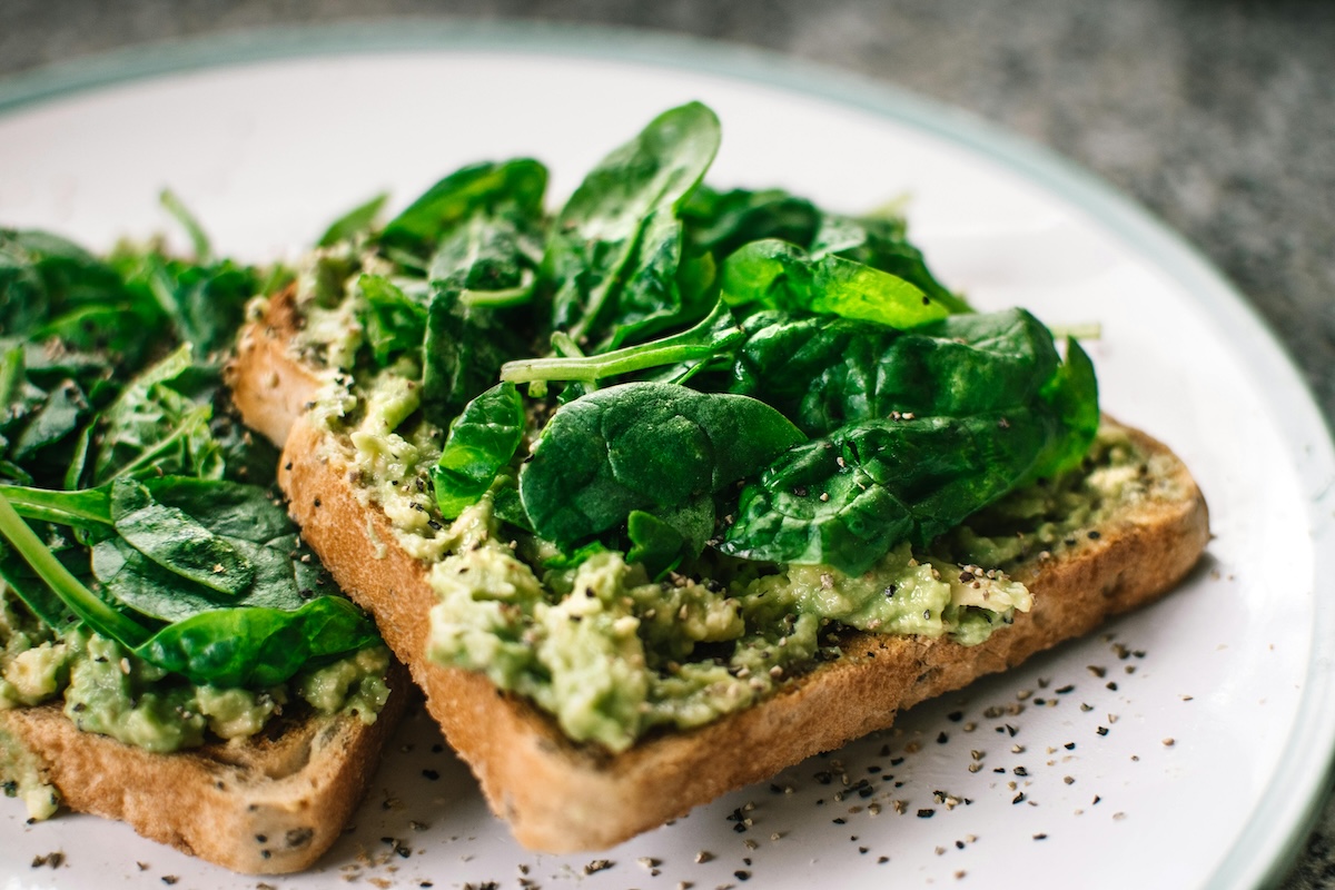 avocado toast and basil on a white ceramic plate