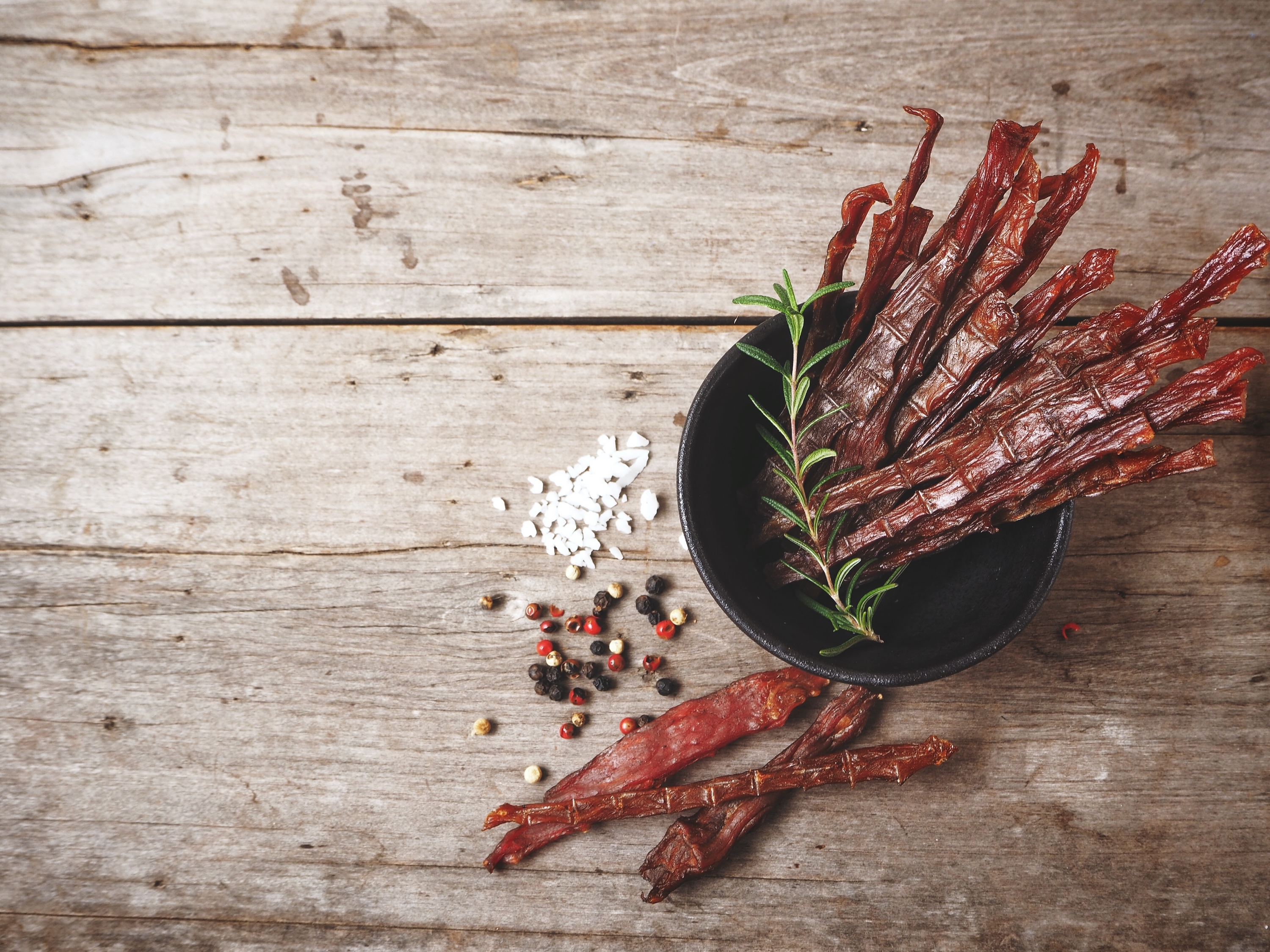 beef jerky sticks in black container on wooden table