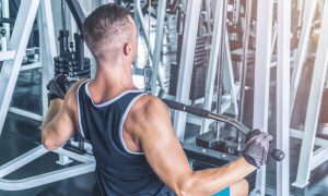 Muscular man using pull-down machine in the gym