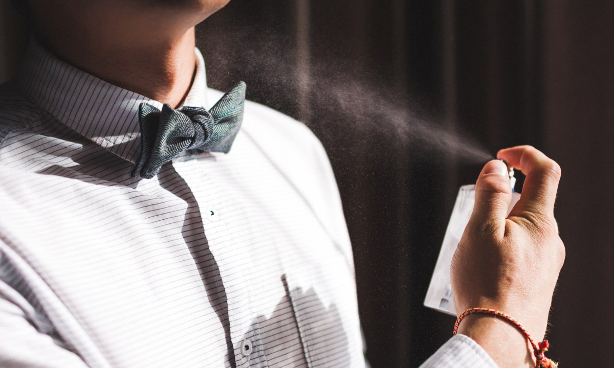 Man applies spray cologne and smells the fragrance