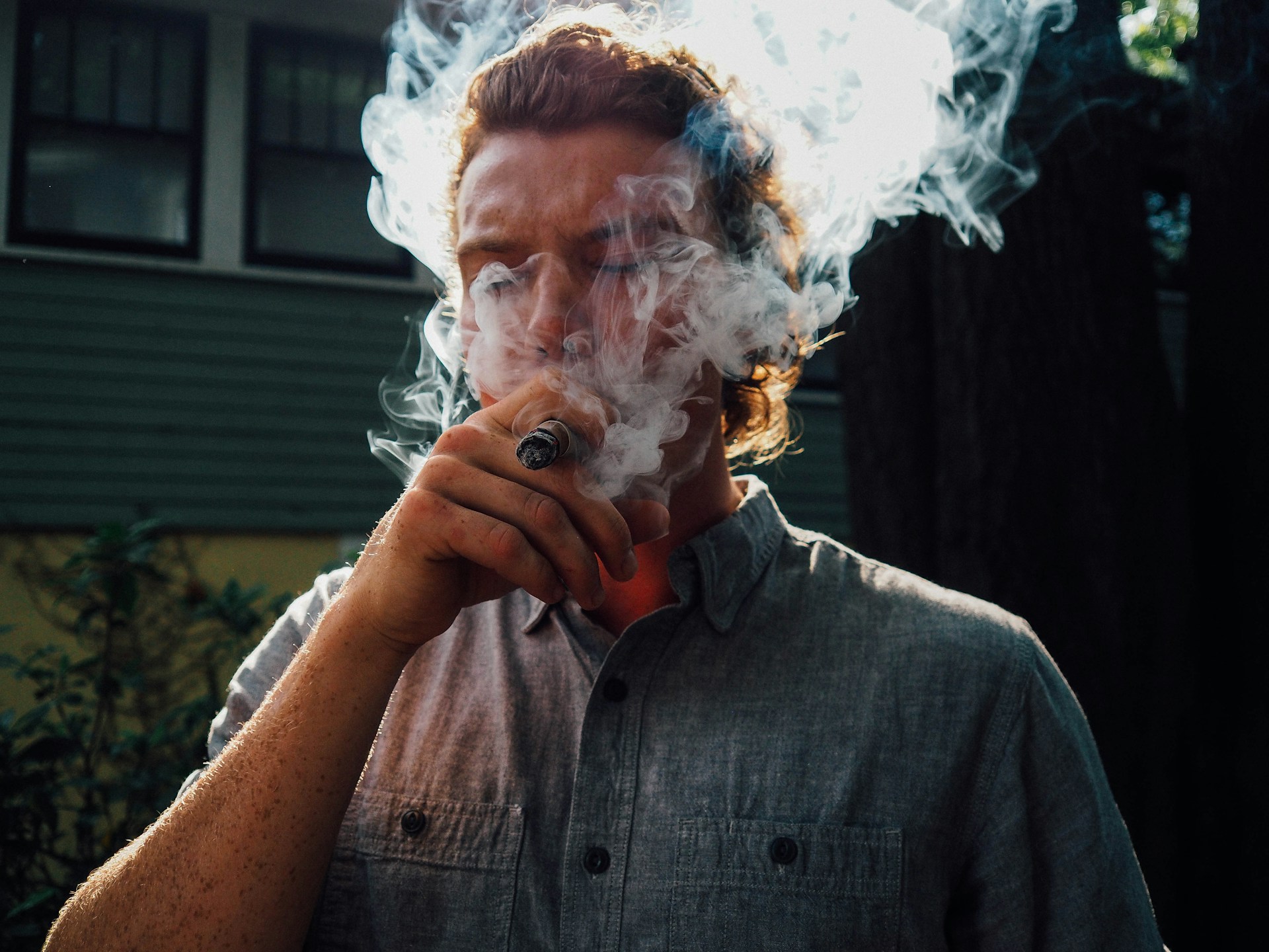 Man smoking cigar casually outside his home, best medium bodied cigars.