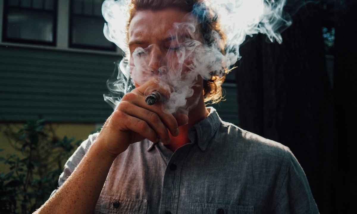 Man smoking cigar casually outside his home, best medium bodied cigars.