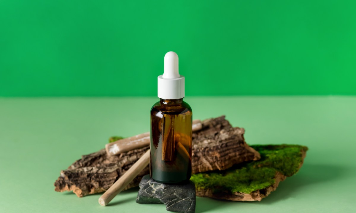 bakuchiol benefits for skin serum glass bottle green background composition with natural materials  tree bark stones wooden s