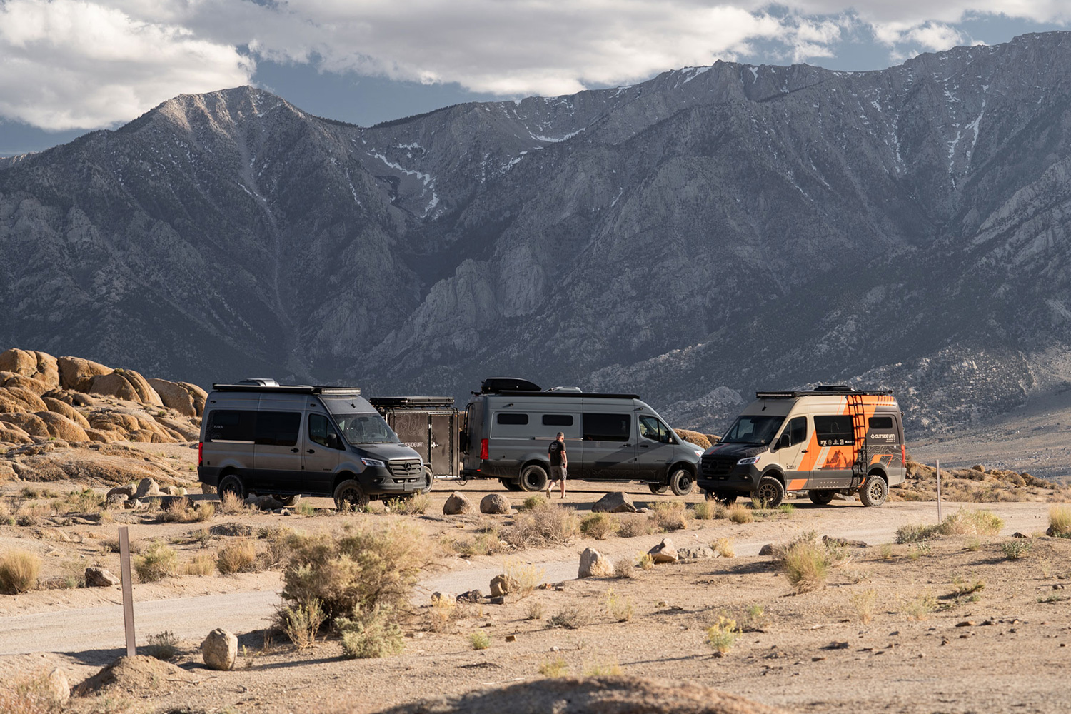 Three Outside Van camper vans parked in the desert.