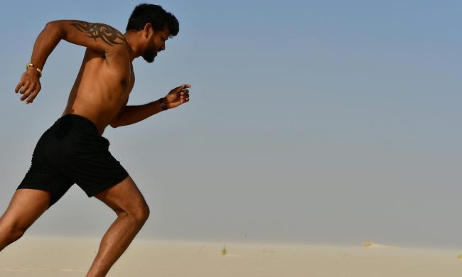 a close up of a shirtless man running outside