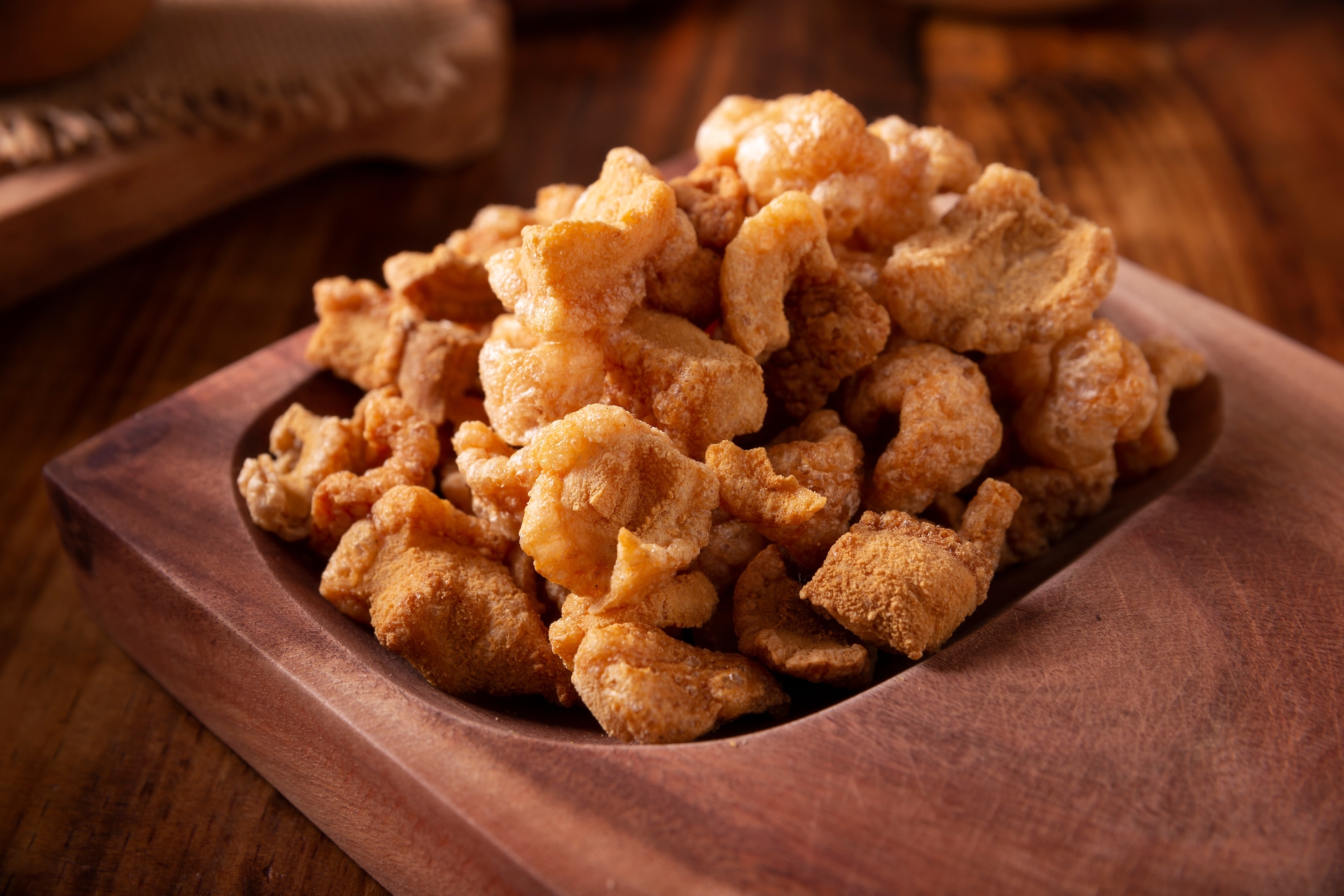 Chicharrones. Deep fried pork rinds, crispy pork skin pieces, traditional mexican ingredient or snack served with lemon juice and red hot chili sauce.