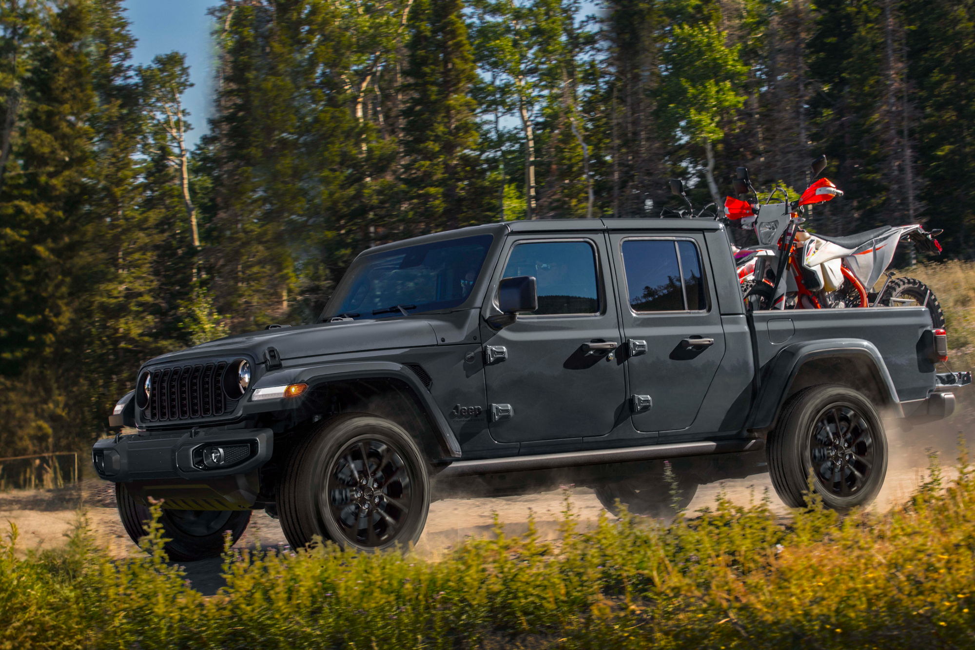 2024 Jeep Gladiator Nighthawk limited edition of 200 driving on a dirt road in a forest,