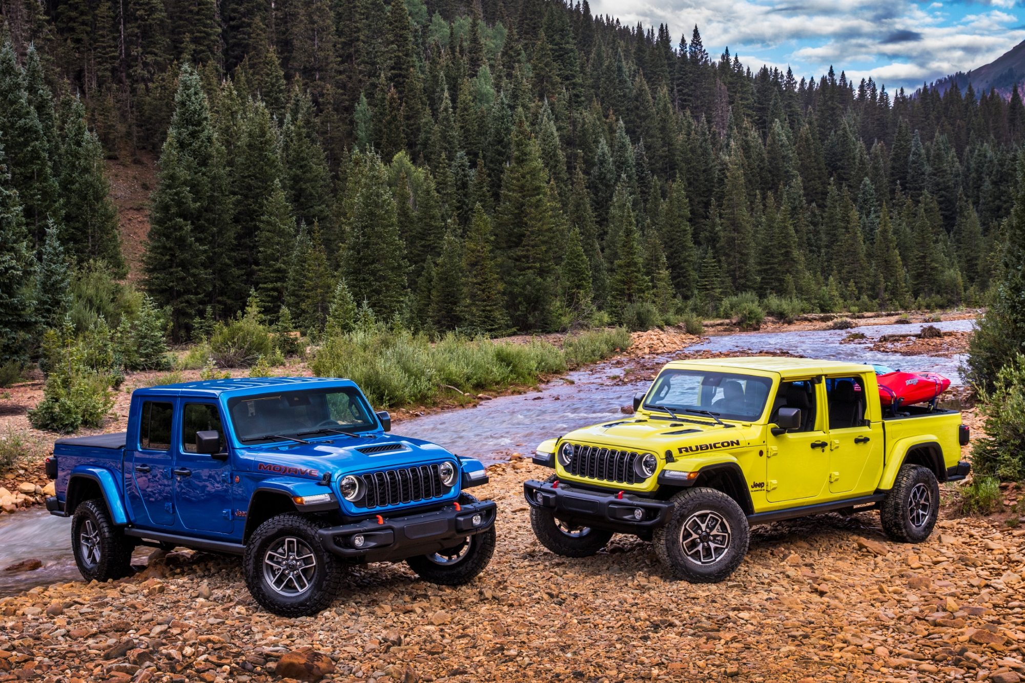 Blue and Yellow 2024 Jeep Gladiator Rubicons parked on a rocky landing on the side of a shallow mountain river.