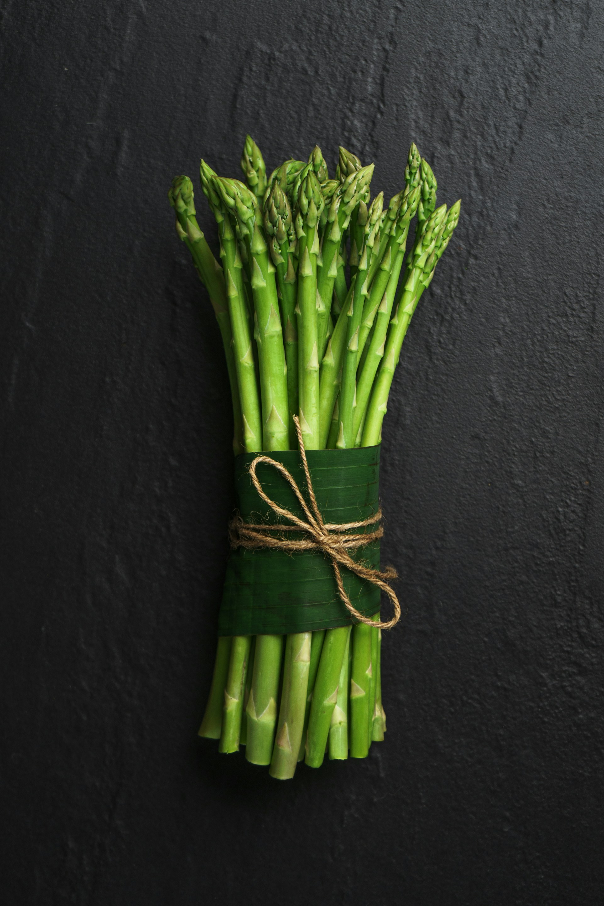 asparagus wrapped in a bunch on a rope with a black background