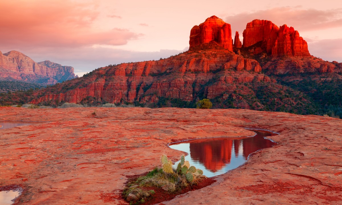 Cathedral Rock in the distance is reflected in a pool of water at sunset, Sedona, Arizona