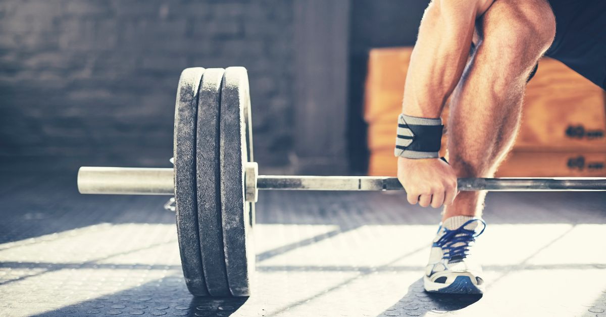 muscular man deadlifting barbell in gym