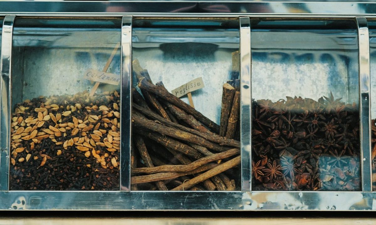 Various flavor items in a cabinet like cinnamon sticks and vanilla.