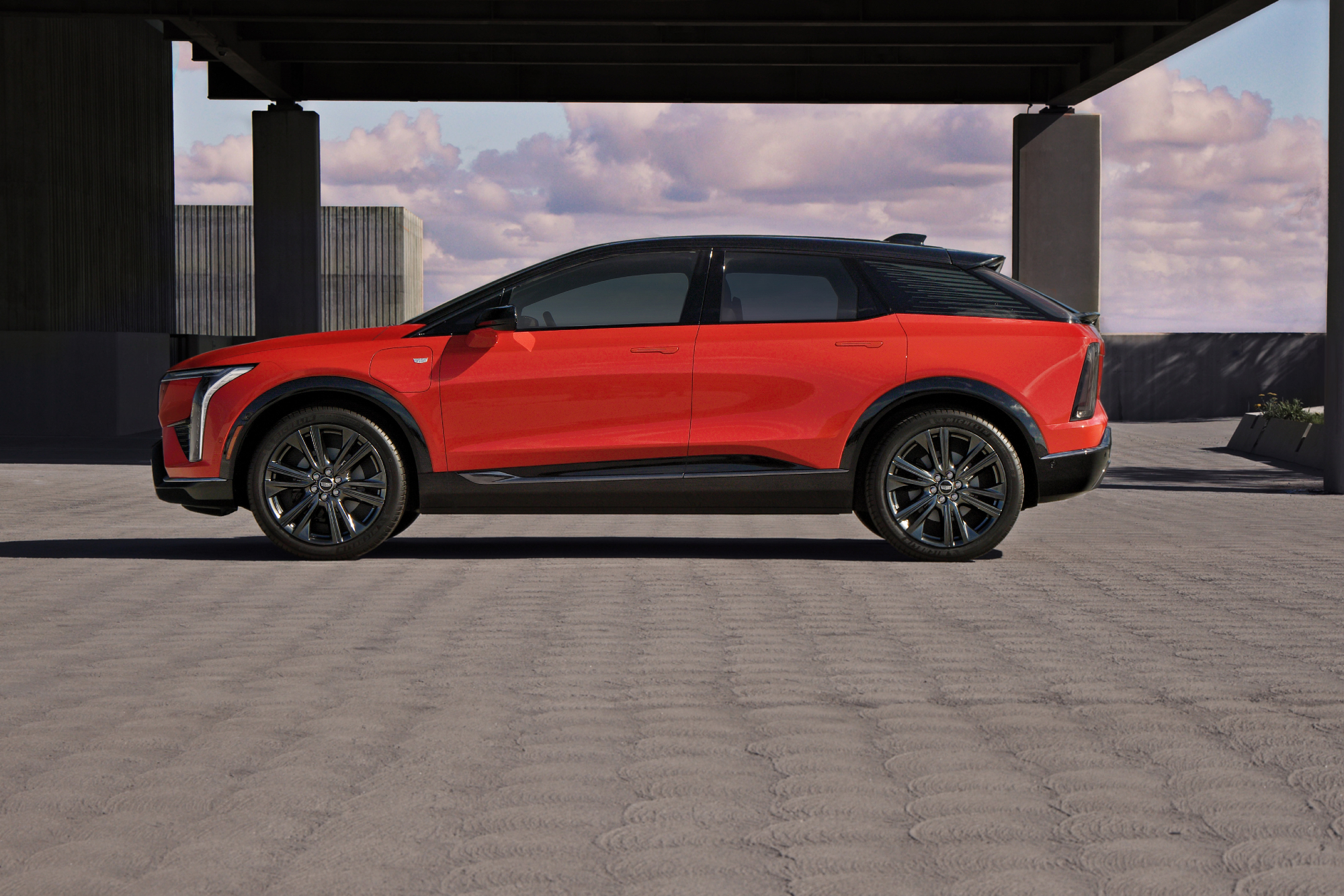 2025 Cadillac Optiq left side profile view parked on a concrete rooftop of a contemporary building.