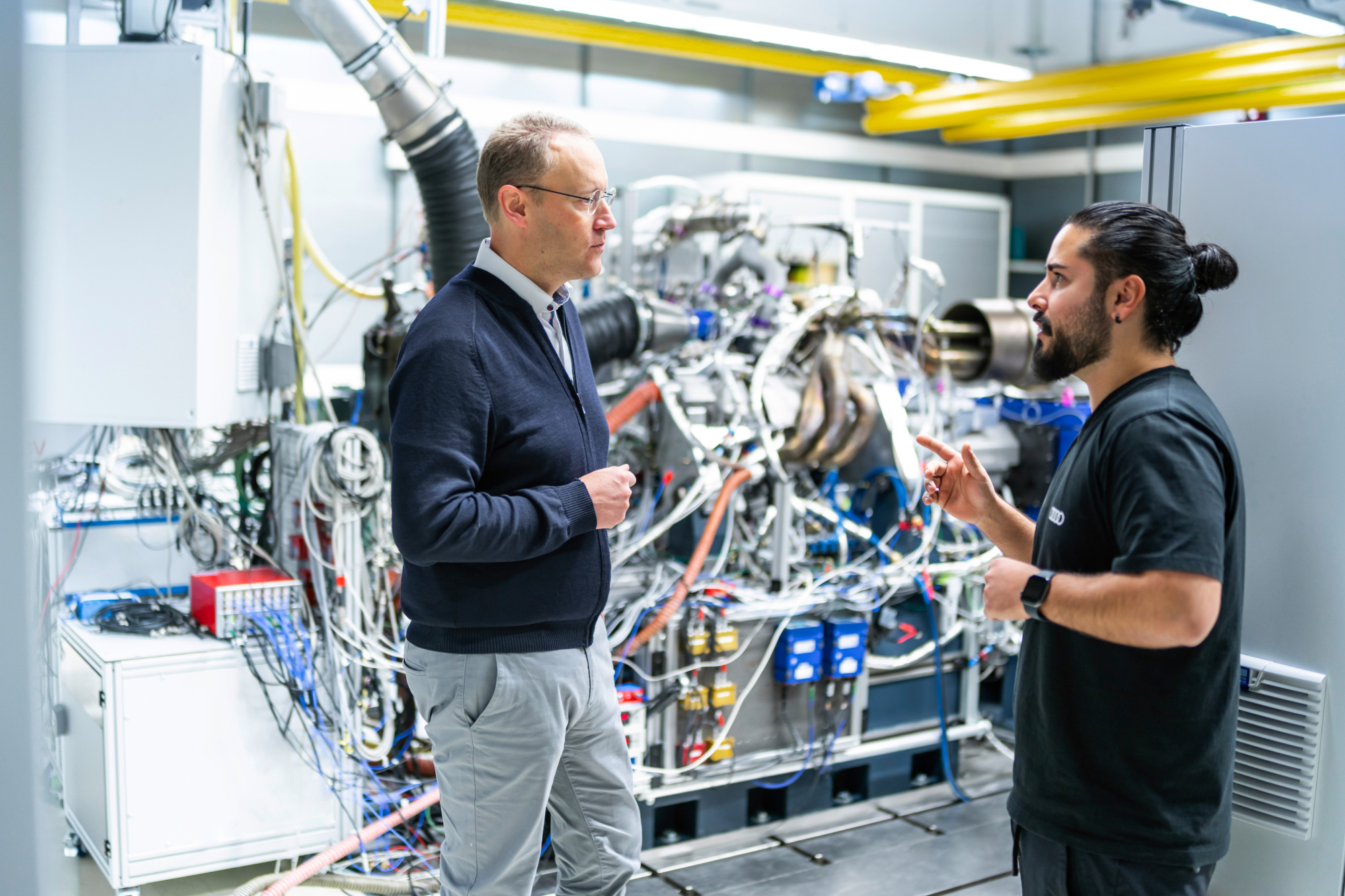 Audi Formula Racing GmbH CTO Stefan Dreyer talking with an engineer at one of th Audi Power Unit test benches.