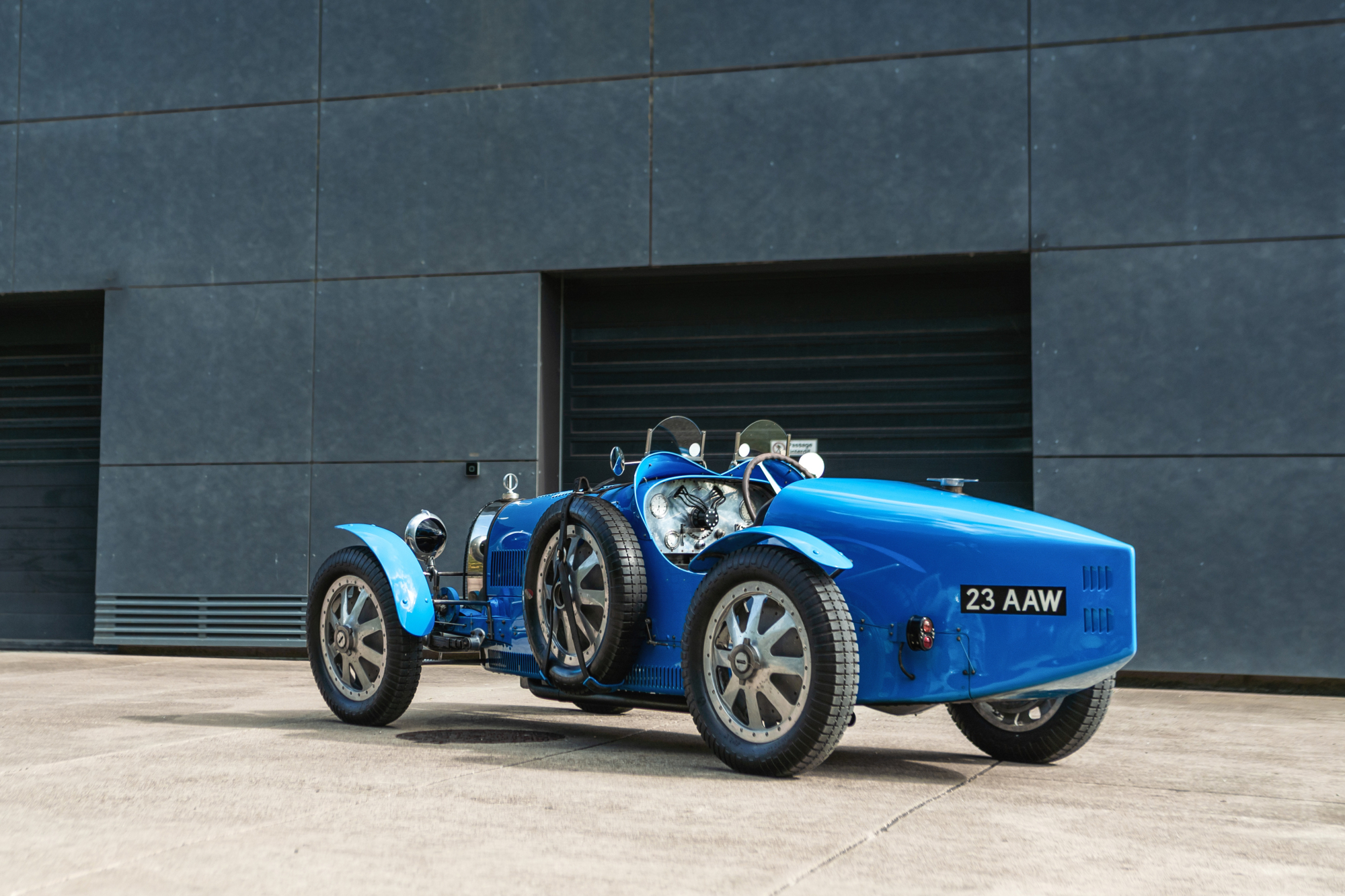 Bugatti Type 35 race car parked by a stone building.