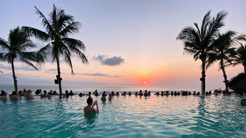 People in a pool watch the sunset in Bali