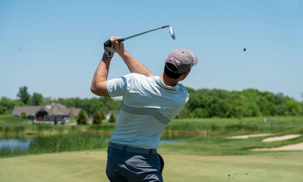 A person swinging a club on the golf course.
